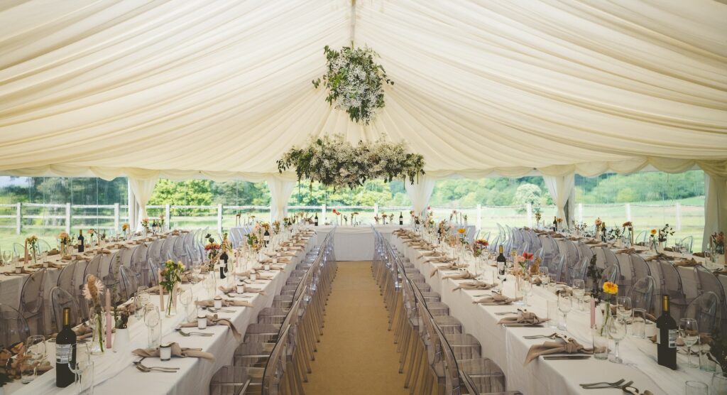 Elegant bespoke marquee wedding reception at The Citadel with long banquet tables, ghost chairs and suspended floral installations