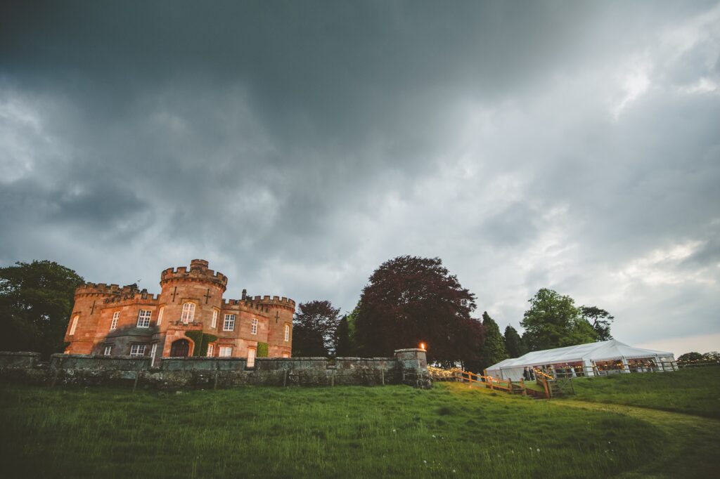 The Citadel's castle-style country house and bespoke wedding marquee illuminated at dusk during a spring wedding in Shropshire