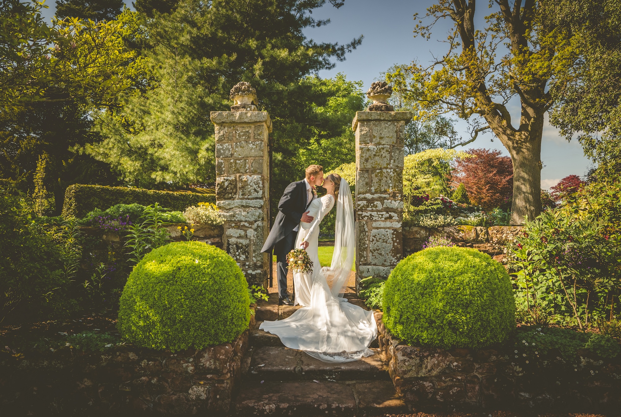 Bride and groom sharing a kiss in The Citadel's walled garden surrounded by beautifully landscaped gardens in North Shropshire